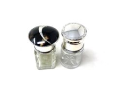 Two silver-lidded glass dressing table bottles, one inset with tortoiseshell.