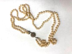 A double strap of pearls on white gold clasp set with a ruby