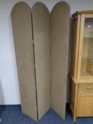 A three-way folding room divider upholstered in a brown beige fabric