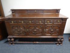 An Edwardian oak three door three drawer sideboard on a raised barley twist base