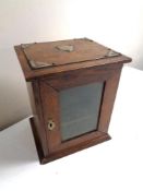 An Edwardian oak glazed door smoker's cabinet.