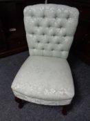 A contemporary buttoned bedroom chair in green fabric