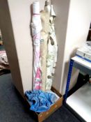 A box of three rolls of upholstery fabric together with a fringed rug