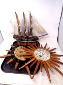 A tray of two teak sunburst wall clocks together with a model of a galleon