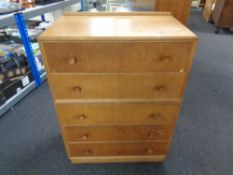 A mid century oak five drawer chest