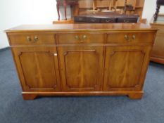 An inlaid yew wood three drawer three door sideboard