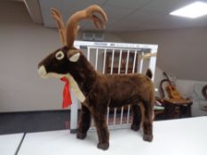 A metal baby gate together with a large reindeer soft toy.