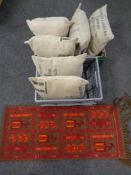 A box containing six contemporary cushions in the form of coffee sacks with a fringed Persian rug