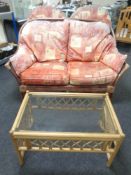 A three piece wicker conservatory suite comprising of two-seater settee and a pair of arm chairs