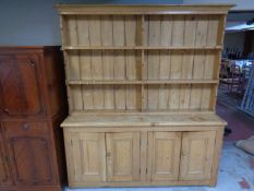 An antique stripped pine four door kitchen dresser with plate rack