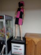 A shop mannequin in 60's dress on a Carnaby Street London wooden plinth.