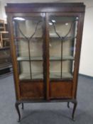 An Edwardian mahogany double door display cabinet on raised cabriole legs.