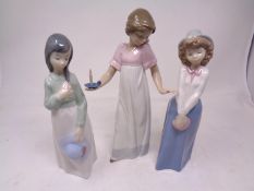 A Nao figure- Girl with candle, together with two further Nao figures.