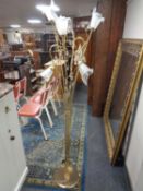 A brass six way floor standing lamp with glass shades in the form of flowers and crystal drops.