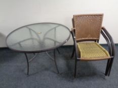 A circular metal glass topped patio table together with a set of four stacking metal and rattan