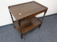 A 20th century oak barley twist two tier trolley with pie crust gallery.