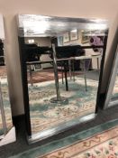 A contemporary mirror in a black frame, 81cm x 106cm.