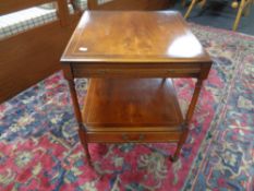 A Regency style two tier occasional table on brass castors fitted with a drawer and slide.