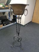A copper planter on a wrought iron stand.