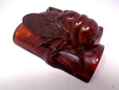 A carved resin figure of an insect on a branch.