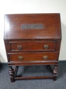 An early 20th century oak writing bureau on raised legs, fitted with two drawers.