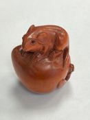 A carved fruitwood netsuke - rat seated on fruit
