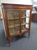 A 19th century inlaid mahogany double door display cabinet on raised legs.