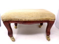 A 19th century beechwood foot stool on brass castors.