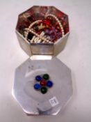 An octagonal plated trinket box containing a small quantity of costume jewellery.