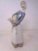 A Lladro figure of a woman carrying a lamb.