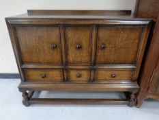 An oak three door sideboard on raised legs.