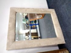 A bevel edge mirror in contemporary frame upholstered in a suede fabric (diameter 106cm).