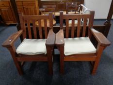 A pair of Barlow Tyrie heavy teak garden armchairs with cushions.