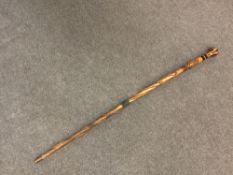 A wooden military staff, carved with serpents and the Royal Crest, with turned specimen wood pommel,