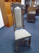 An 18th century carved oak high backed hall chair in tapestry fabric