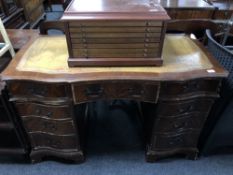 A mahogany shaped front nine drawer twin pedestal writing desk with tooled leather top