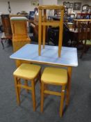 A mid-20th century melamine topped kitchen table together with a set of three stools.
