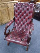 A stained beech scroll armchair upholstered in Burgundy buttoned and studded leather.