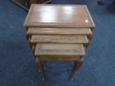 A nest of four carved Indian style tables, one fitted with a drawer.