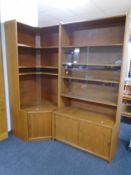A 20th century teak two piece corner book case fitted with cupboards below.