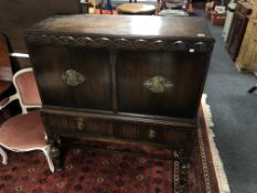 An Edwardian carved oak four door sideboard on raised legs fitted with drawers beneath.