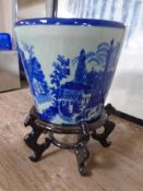A blue and white glazed ceramic ironstone planter on a wooden stand.