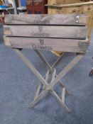 A set of three graduated pine trays bearing Guinness advertising on stand.