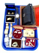 A tray containing carved wooden trinket boxes, leather purses, wristwatches, costume brooches,