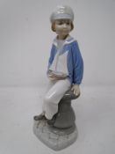 A Lladro figure of a boy in sailor suit with pond yacht.