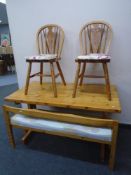 A pine refectory table together with a pair of wheelback chairs and a bench.