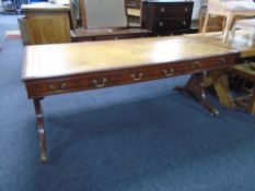 A mahogany three-drawer sofa table with brown leather top with brass-capped feet