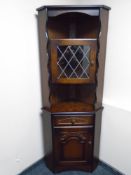 A corner display cabinet fitted with cupboards in oak finish