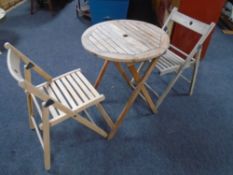 A folding teak patio table together with two chairs.