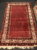 An Iranian rug on red ground, 129cm by 213cm.